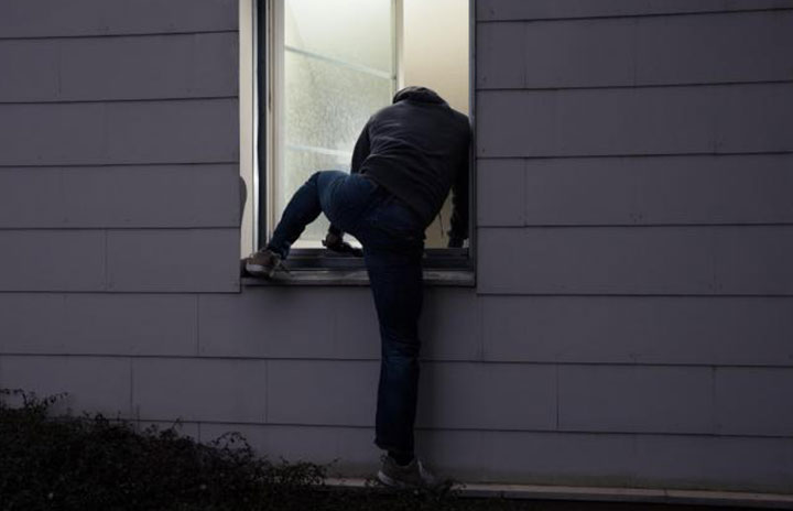 Burglar climbing through window
