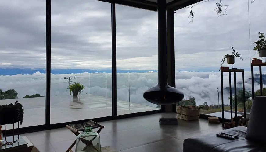 Living room with glass walls looking out above clouds
