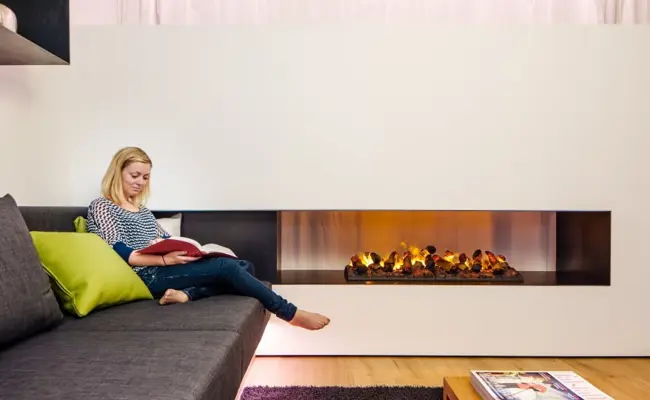 Woman sitting on a sofa next to a cozy fire