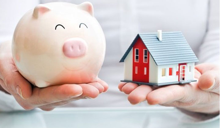 Hands holding piggy bank and house next to each other