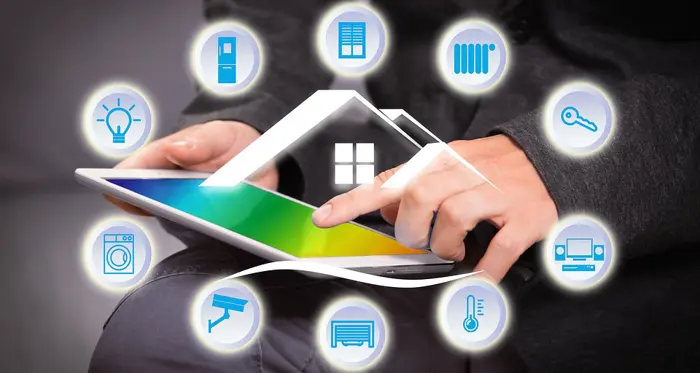 Man holding tablet with various smart home icons displayed around it